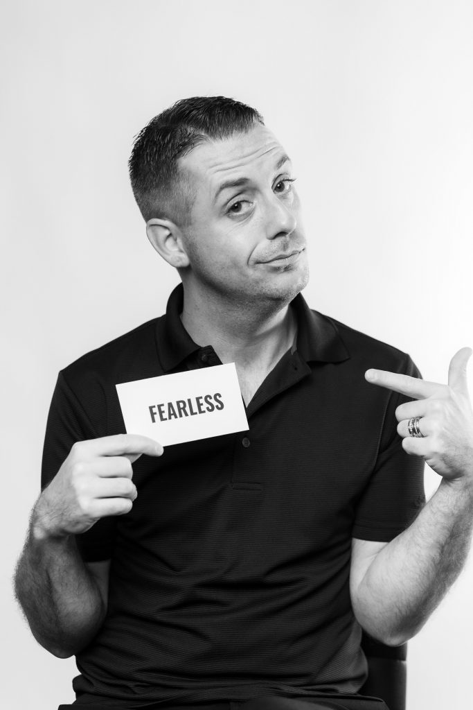 black and white photo of guy holding card that says fearless